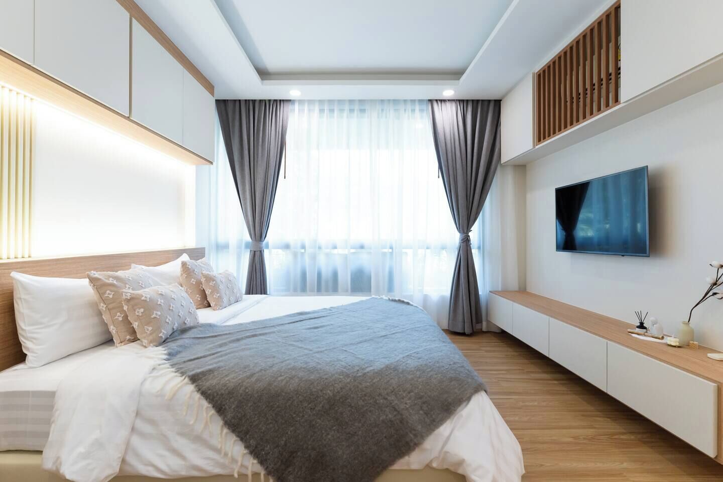 Un dormitorio moderno con una cama grande, un televisor y un banco de madera.