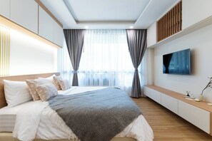Un dormitorio moderno con una cama grande, un televisor y un banco de madera.