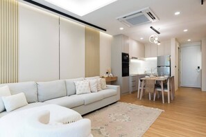Una sala de estar moderna con un sofá, una mesa de comedor con sillas y una zona de cocina con electrodomésticos.