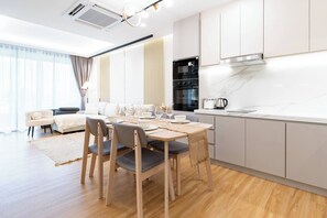 Una cocina moderna con zona de comedor, suelo de madera y un amplio ventanal con cortinas.