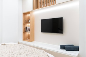 Un dormitorio moderno con una cama grande, un televisor integrado y una estantería de madera.