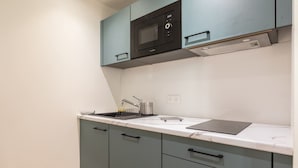 A kitchen with light blue cabinets, a black microwave, and a white countertop.
