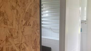 Une salle de bain avec des carreaux blancs, un mur en bois, des toilettes noires et un rideau de douche blanc.