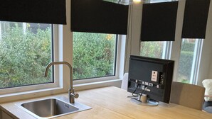 Una cocina moderna con un lavamanos de acero inoxidable, una placa de inducción negra y un horno empotrado.
