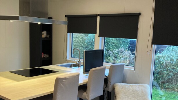 Una cocina moderna con estufa integrada, una zona de comedor con cuatro sillas y un ventanal con vistas a zonas verdes.