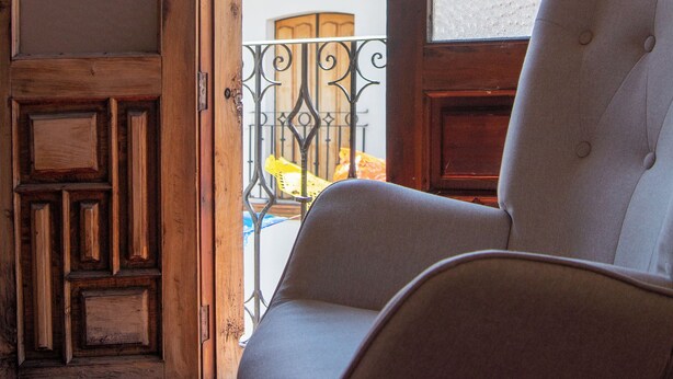 A wooden door with glass panels leading to a balcony with a chair and a lamp.