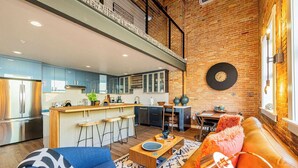A modern kitchen with a central island, a dining area with a table and chairs, and a living area with a sofa and a coffee table. - Historic Bldg on Washington Blvd | Patio & BBQ (Ogden)