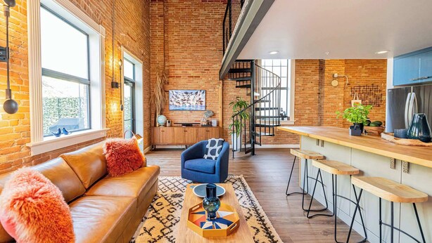 A modern kitchen with a brick wall, wooden bar counter, and a staircase leading to an upper level. - Historic Bldg on Washington Blvd | Patio & BBQ (Ogden)