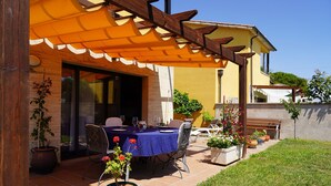An outdoor patio with a table set for dining, surrounded by chairs and potted plants.