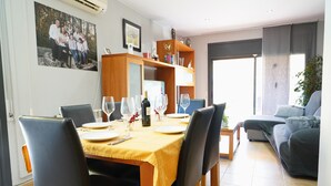 A dining area with a table set for four, a bookshelf, and a sofa in a living room.