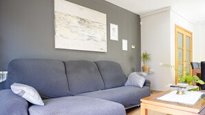 A living room with a grey sofa, a small wooden table, and a large abstract painting on the wall.