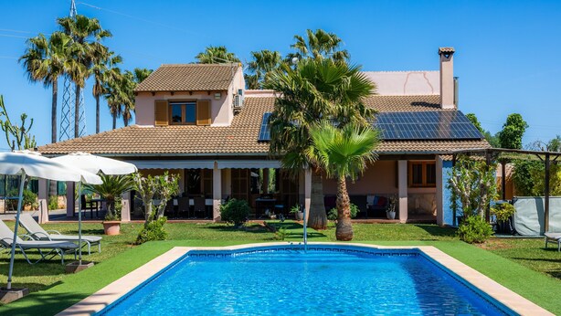 A house with a swimming pool, palm trees, and a solar panel. - Country House 'Ca Na Bisquerra' with Mountain View, Wi-Fi and Air Conditioning (Santa Margalida)