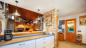 A kitchen with a stone accent wall, wooden beams, and a coffee maker on the counter. - Country House 'Ca Na Bisquerra' with Mountain View, Wi-Fi and Air Conditioning (Santa Margalida)