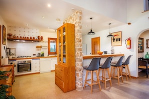 A kitchen with a stone column, wooden cabinets, and bar stools.