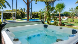 A hot tub with a view of a pool and palm trees. - Country House 'Ca Na Bisquerra' with Mountain View, Wi-Fi and Air Conditioning (Santa Margalida)
