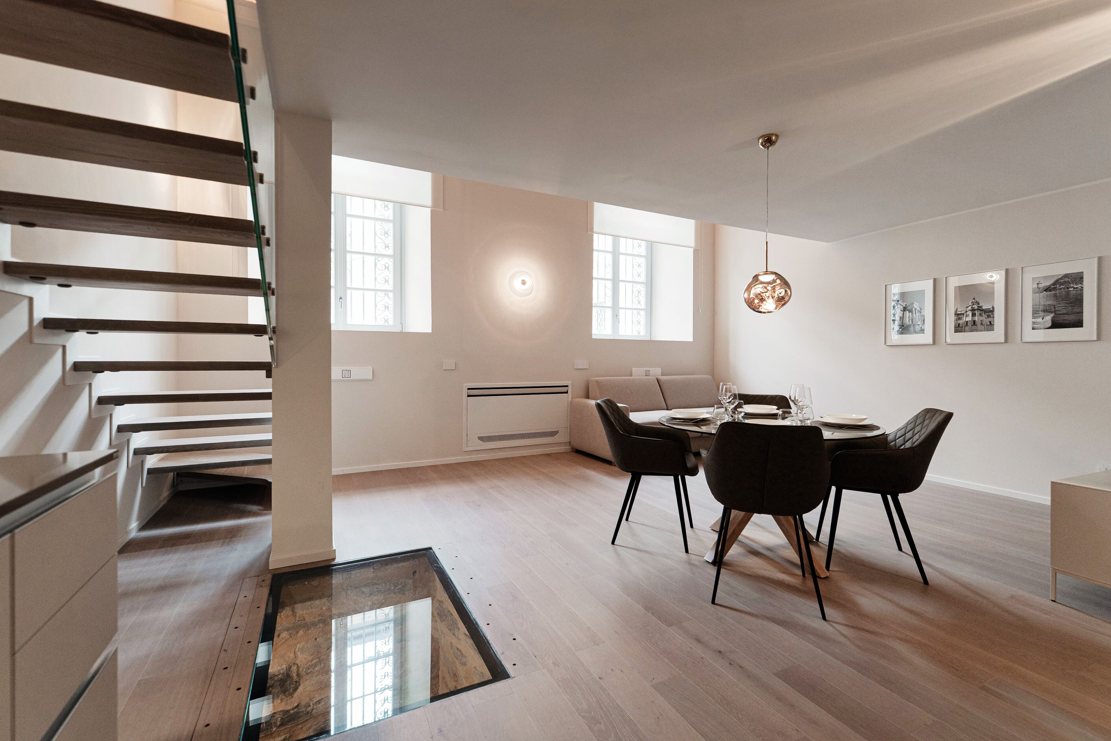 Un espace repas moderne avec un plancher en bois, une table ronde et des chaises noires.