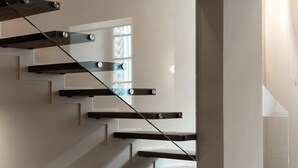 Una escalera moderna con barandillas de cristal y escalones de madera.