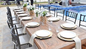 A dining table set for a meal with chairs, a pool, and a grill in the background. - Chácara completa 5 quartos piscina, sauna, jacuzzi, churrasqueira e fogão lenha (Pouso Alegre)