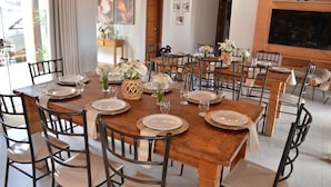 A dining area with multiple tables set for a meal, featuring wooden tables, black chairs, and white plates. - Chácara completa 5 quartos piscina, sauna, jacuzzi, churrasqueira e fogão lenha (Pouso Alegre)