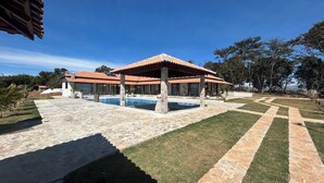 A property with a swimming pool, covered patio, and stone pathways. - Chácara completa 5 quartos piscina, sauna, jacuzzi, churrasqueira e fogão lenha (Pouso Alegre)