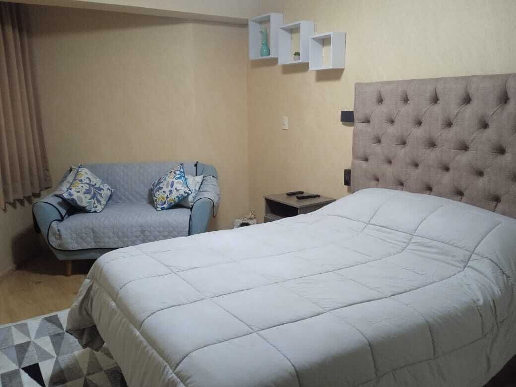 A hotel room with a large bed, a sofa, and a small table.