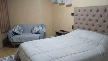 A hotel room with a large bed, a sofa, and a small table.