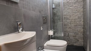 A modern bathroom with a shower, toilet, and bidet.