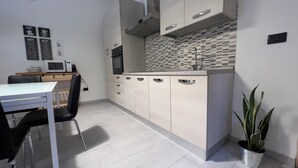 A modern kitchen with white cabinets, a built-in microwave, and a tiled backsplash.