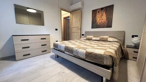 A bedroom with a bed, a dresser, a door, and a painting on the wall.