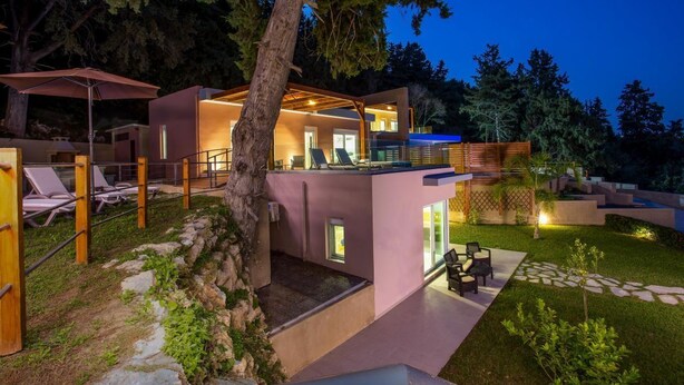 Een modern huis met een glazen balkon, zitplaatsen buiten en een pad van stenen.