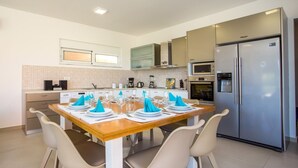 Een moderne keuken met een eettafel gedekt voor zes personen, voorzien van een koelkast, magnetron en oven.
