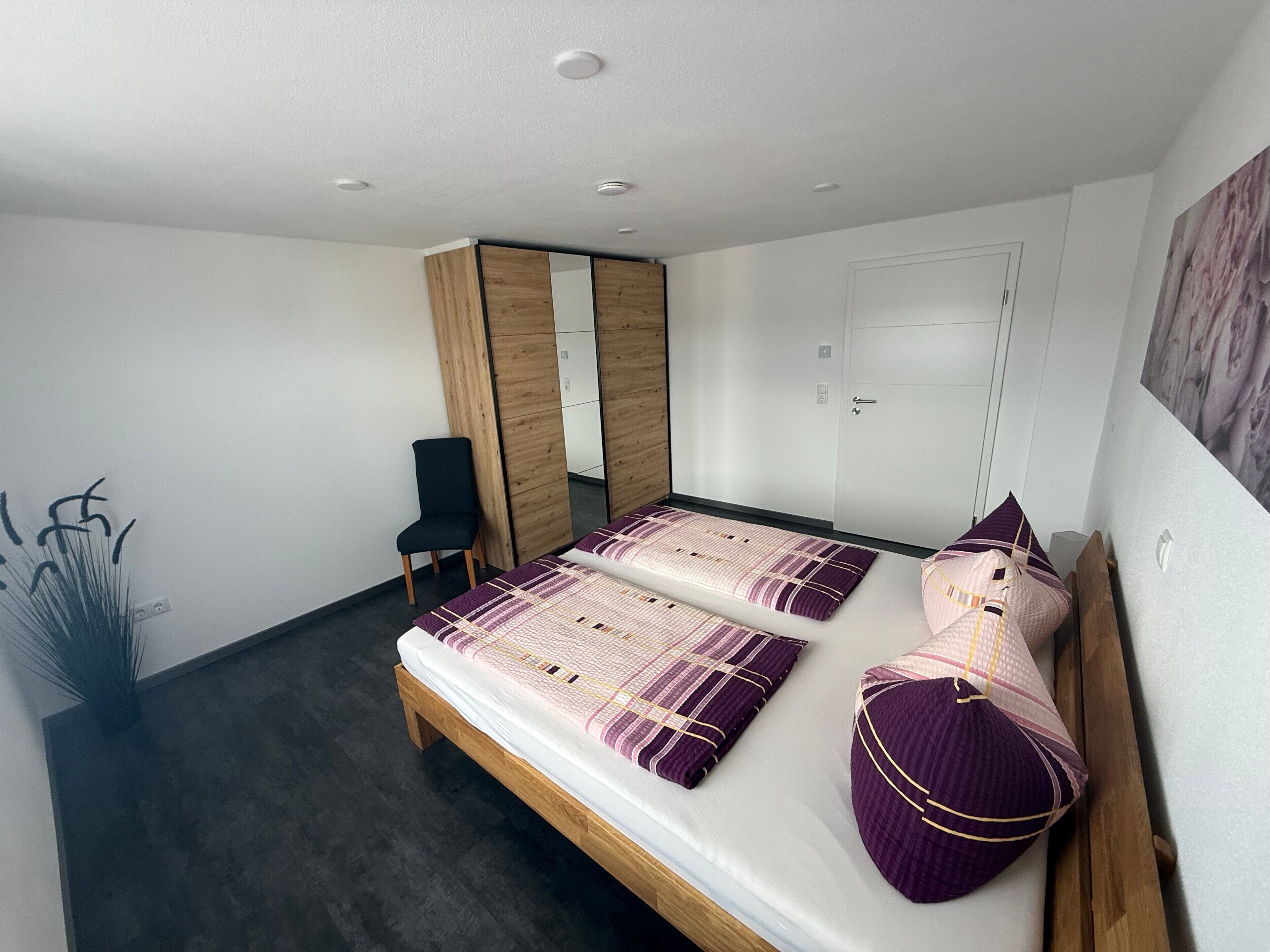 Une chambre à coucher avec un lit, une chaise, une armoire et une porte.