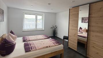 A modern bedroom with a large bed, a window, and a mirror.