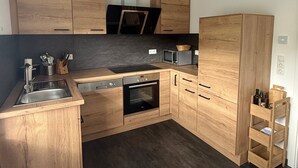 Une cuisine moderne avec des meubles en bois, un four encastré et un four à micro-ondes.