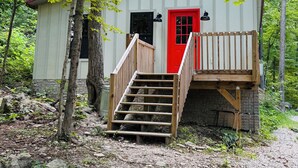 Eine Holzhütte mit roter Tür, Holzstufen und einem Steinfundament.