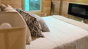 Ein Holzhäuschen-Zimmer mit Bett, Fenster und Fernseher.