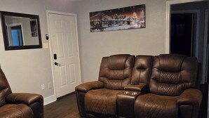 Un salon avec un canapé en cuir marron, un fauteuil en cuir marron et un ventilateur de plafond.