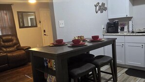 Une cuisine moderne avec des meubles blancs, une table en bois foncé et un ventilateur de plafond.