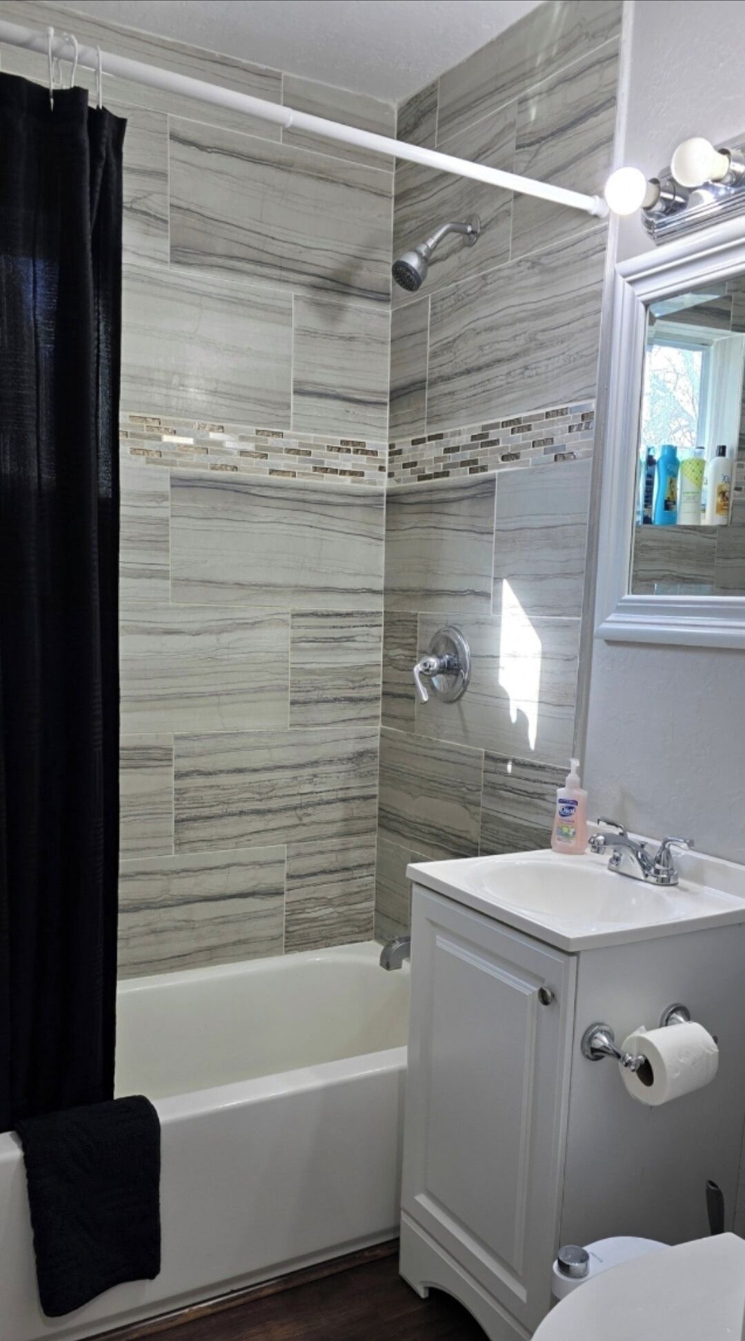 A bathroom with a bathtub, shower, vanity, and a mirror.