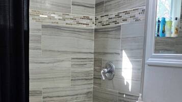 A bathroom with a bathtub, shower, vanity, and a mirror.