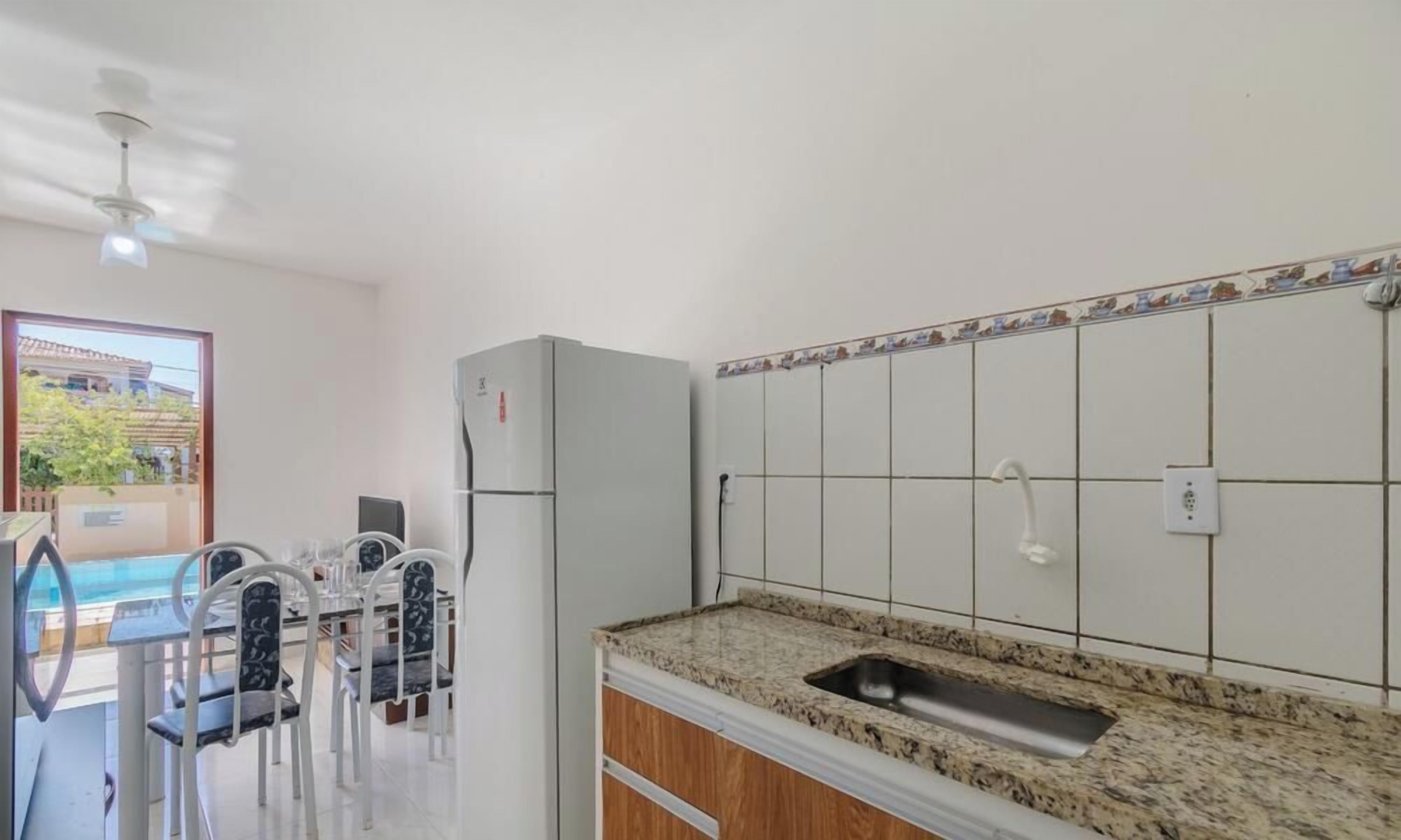 A kitchen with a granite countertop, white tiled backsplash, and a built-in sink.