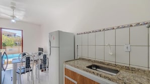 A kitchen with a granite countertop, white tiled backsplash, and a built-in sink. - Cond. c\ Piscina e Churrasqueira a 650 m Praia de Taperapuan \ PFNs (Porto Seguro)