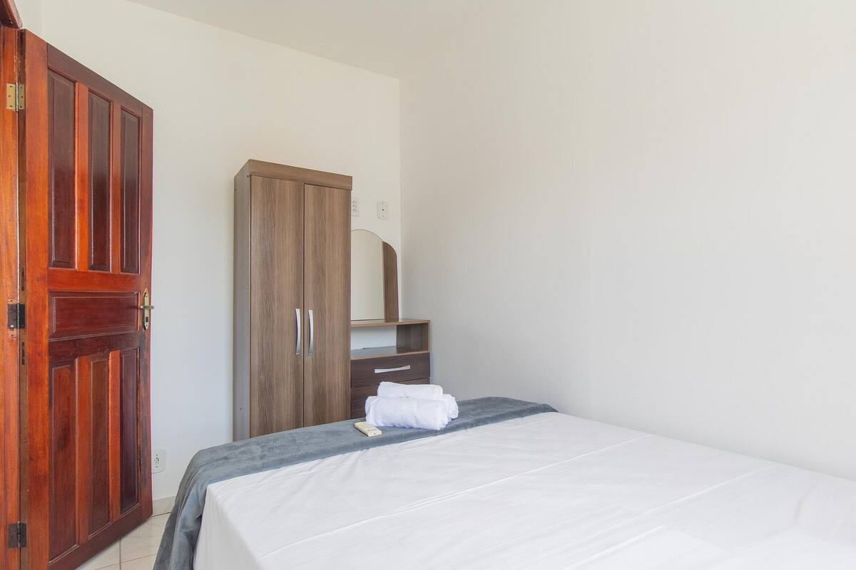 Une chambre à coucher avec un lit, une armoire en bois et une petite étagère.