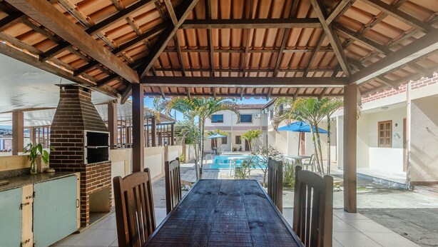 An outdoor patio with a pool, a brick oven, and a covered seating area. - Cond. c\ Piscina e Churrasqueira a 650 m Praia de Taperapuan \ PFNs (Porto Seguro)