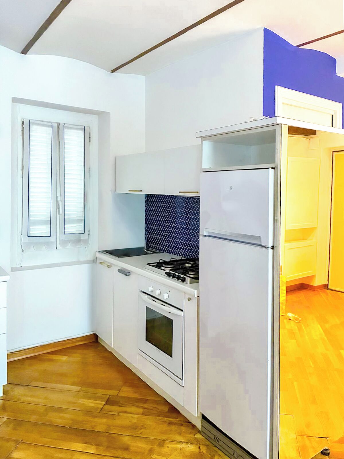 Eine Küche mit weißen Schränken, einem Herd, einem Backofen und einem Kühlschrank.