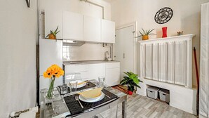Una cocina moderna con armarios blancos, una campana extractora de acero inoxidable y una zona de comedor con mesa de vidrio.