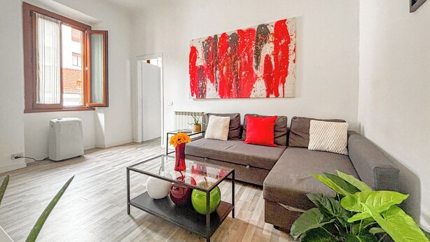 Una sala de estar moderna con un sofá, una mesa de centro de vidrio y un cuadro abstracto grande.