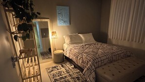 Ein Schlafzimmer mit Bett, Nachttischlampe und einer Pflanze.