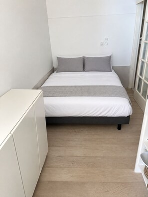 A bedroom with a bed, a bedside table, and a wardrobe.