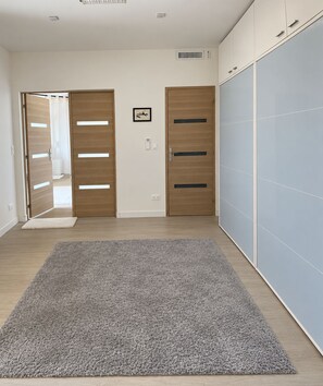 A hallway with a grey carpet, wooden doors, and a wardrobe with sliding doors.